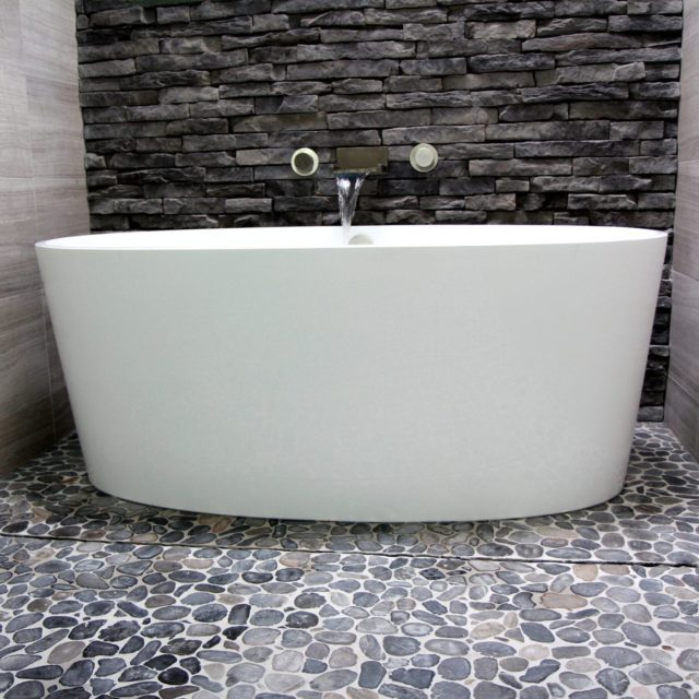 Victoria + Albert IOS bathtub in bathroom with pebble stone floor and hidden drain